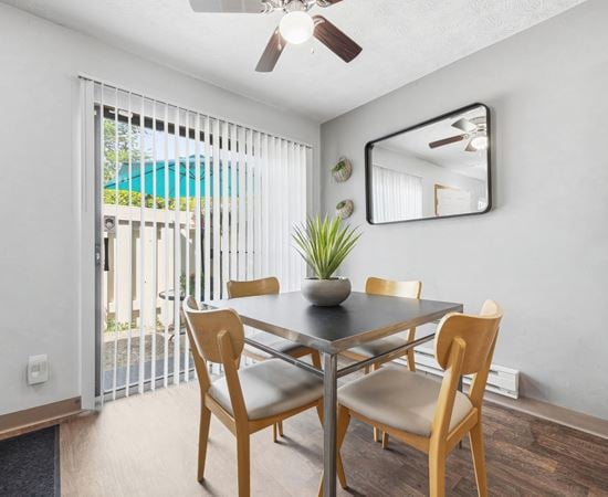 A dining room with a table and chairs and a ceiling fan.